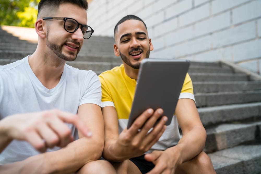 Popular Digital Solutions for Sports and Fans Portrait of happy gay couple spending time together and using a digital table