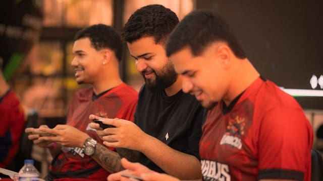 Three men playing mobile games together